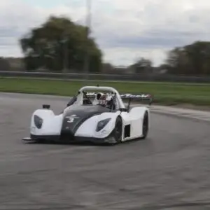 570971314178971389403393012791957543910088549n Elementor Hosted Website Elementor Hosted Website Open-cockpit race car with number 3, white and black livery, taking a turn on a racetrack with a driver in a red helmet.